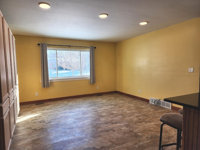 empty room with stone finish flooring, visible vents, and baseboards