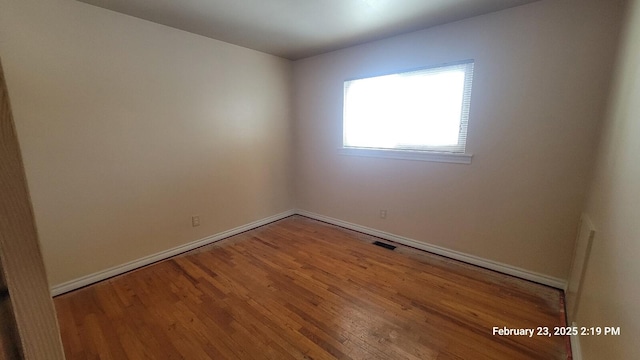 unfurnished room with visible vents, baseboards, and wood finished floors