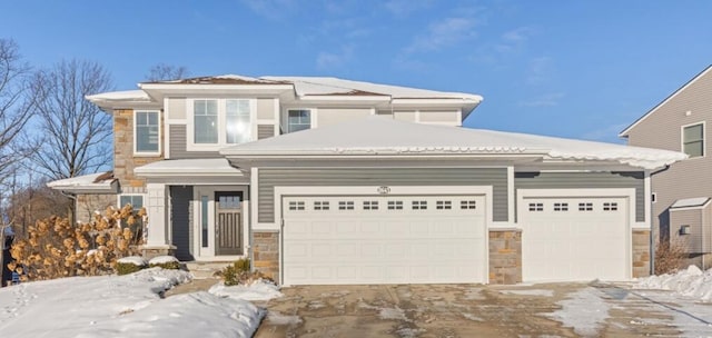 view of front of house with stone siding, an attached garage, and driveway