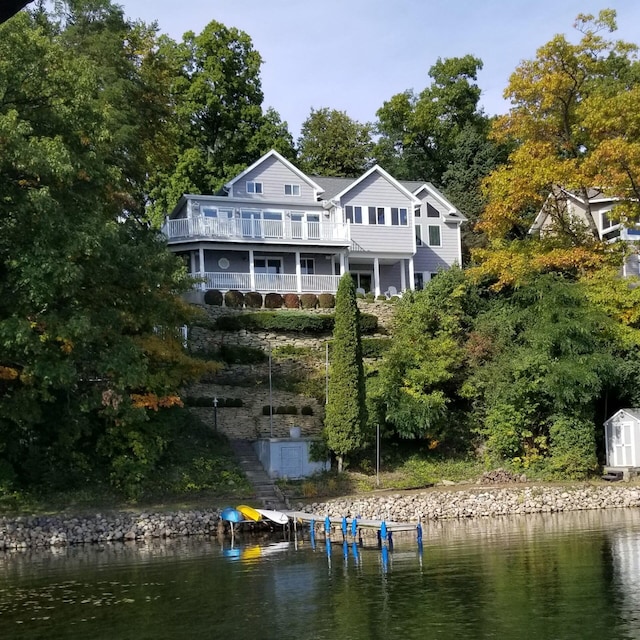 back of property featuring a water view, a shed, and an outbuilding