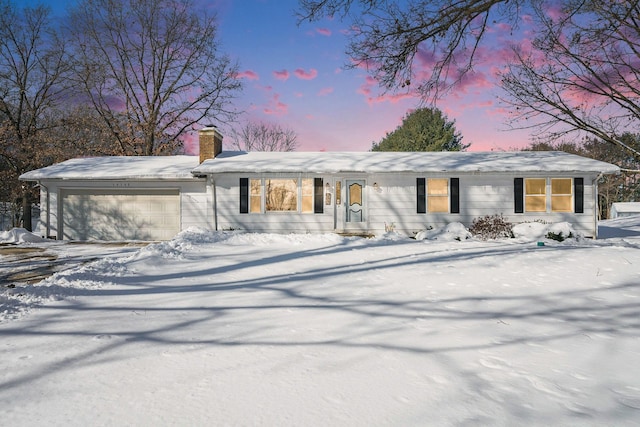 view of front of house featuring an attached garage, driveway, and a chimney