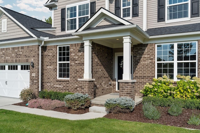 doorway to property with an attached garage, roof with shingles, and brick siding