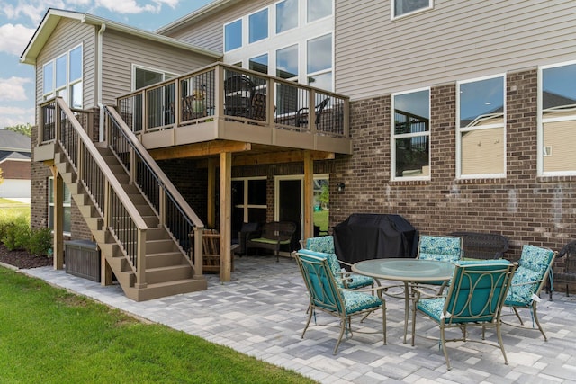 view of patio with a deck, outdoor dining area, stairway, and a grill