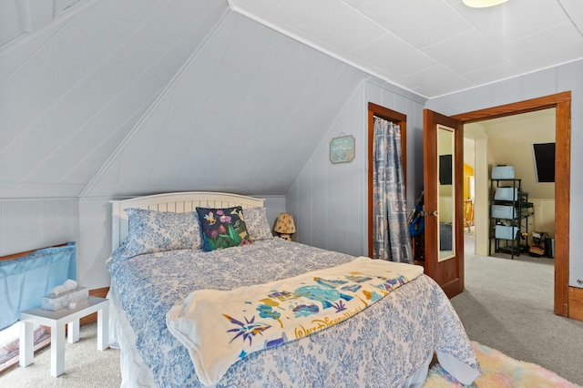 bedroom featuring lofted ceiling, carpet, and a decorative wall