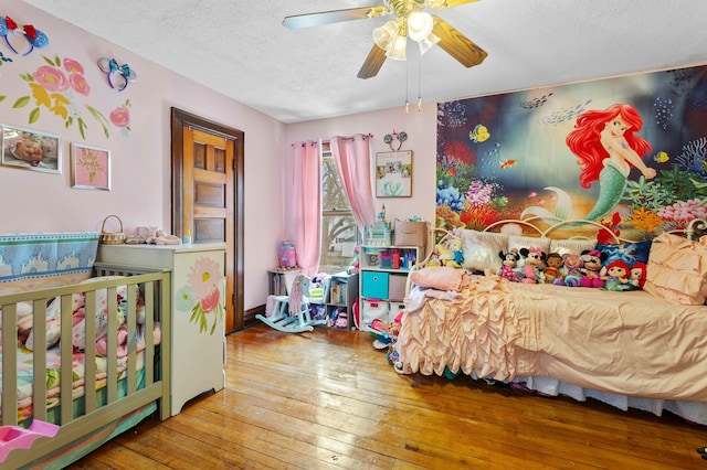 bedroom featuring a textured ceiling, ceiling fan, and wood-type flooring