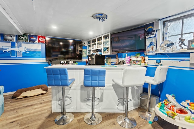 bar with indoor wet bar and wood finished floors