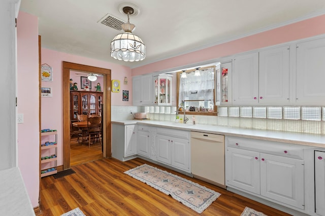 kitchen featuring dishwasher, wood finished floors, light countertops, white cabinetry, and a sink