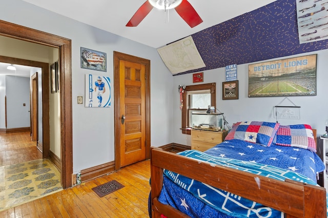 bedroom with lofted ceiling, visible vents, hardwood / wood-style floors, a ceiling fan, and baseboards