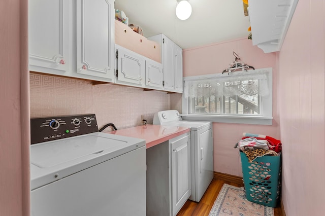 washroom featuring light wood-style floors, cabinet space, and washing machine and clothes dryer