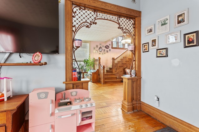 hallway featuring stairway, wood-type flooring, and baseboards