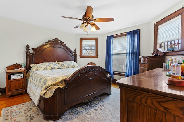 bedroom featuring a ceiling fan, multiple windows, and wood finished floors