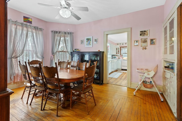 dining area featuring light wood-type flooring, a ceiling fan, and baseboards