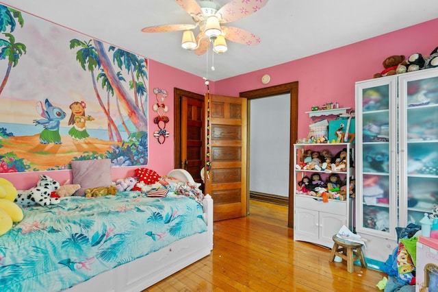 bedroom with light wood finished floors, baseboards, and a ceiling fan