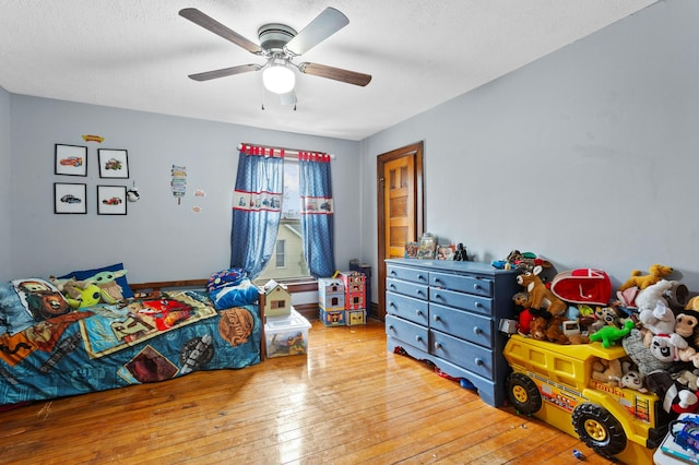 bedroom with a textured ceiling, ceiling fan, and light wood-style flooring