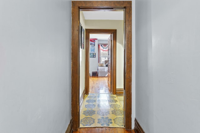 corridor featuring light wood-style flooring and baseboards