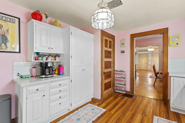 interior space featuring light wood finished floors, white cabinetry, light countertops, and backsplash