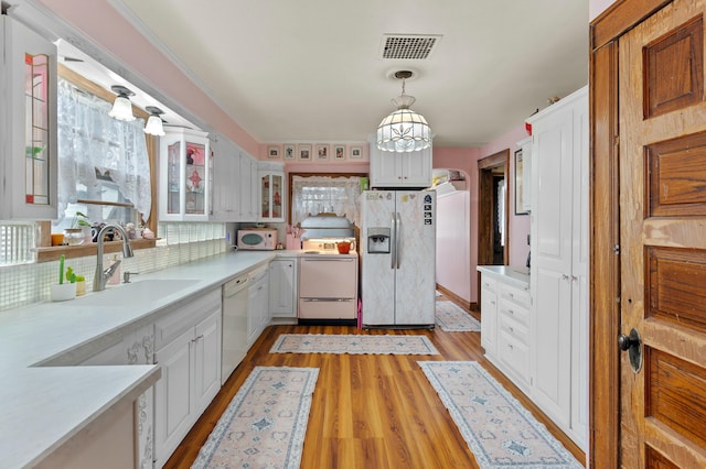 kitchen featuring tasteful backsplash, light countertops, light wood-style flooring, a sink, and white appliances