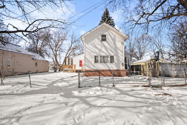 snow covered house featuring fence