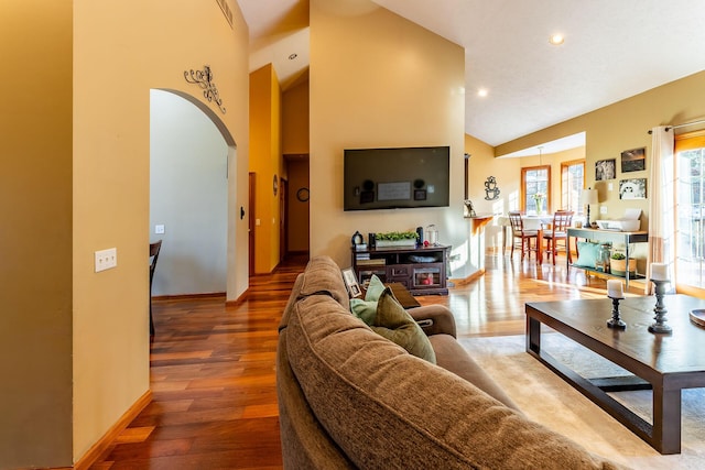 7016 Hyde Park Rd, Whitehall, MI 49461 - living room with high vaulted ceiling, arched walkways, baseboards, wood finished floors, and recessed lighting