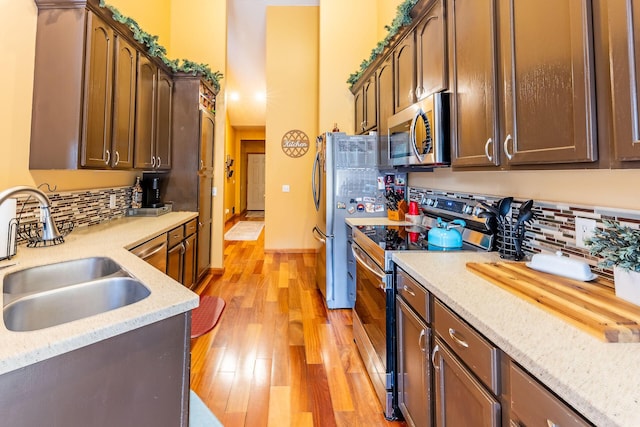 7016 Hyde Park Rd, Whitehall, MI 49461 - kitchen featuring stainless steel appliances, a sink, backsplash, and a towering ceiling