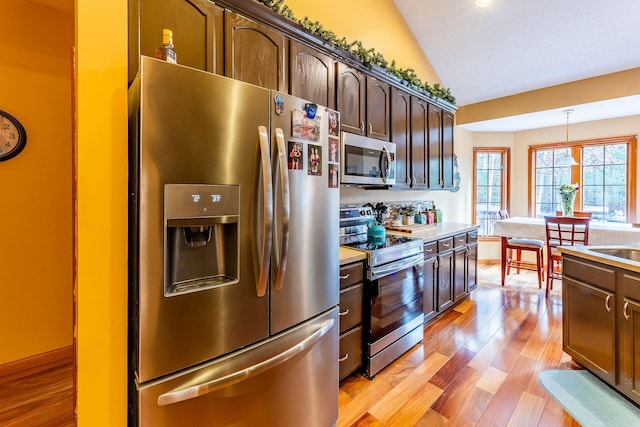 7016 Hyde Park Rd, Whitehall, MI 49461 - kitchen with appliances with stainless steel finishes, lofted ceiling, light countertops, light wood-style flooring, and dark brown cabinetry