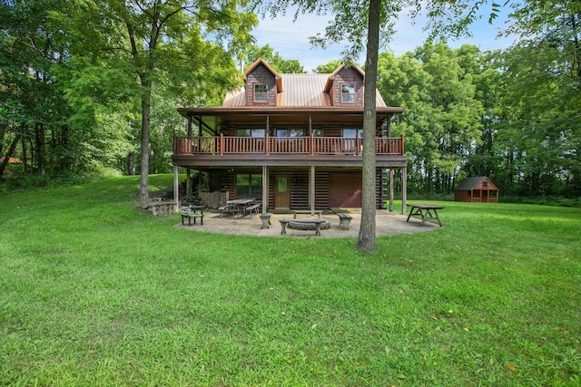 back of house with an outdoor fire pit, metal roof, a lawn, and a patio