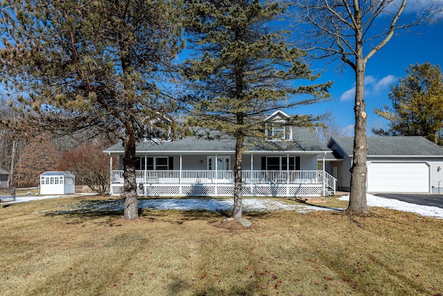 view of front facade with an outbuilding, covered porch, a front yard, a garage, and driveway