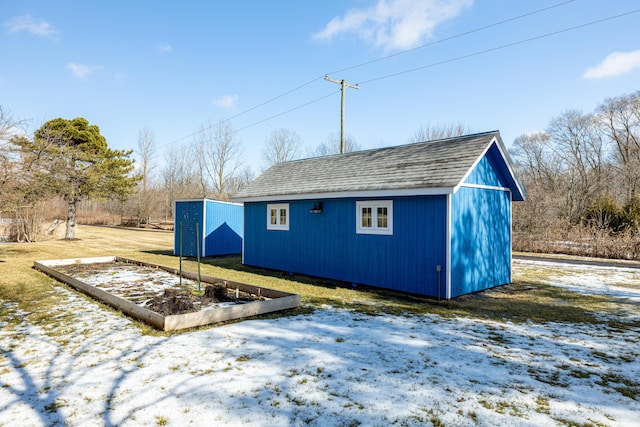 snow covered structure featuring an outbuilding