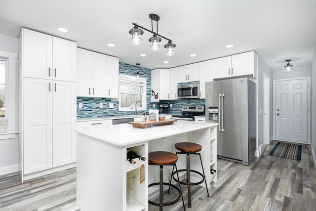 kitchen featuring stainless steel appliances, light countertops, white cabinets, and a sink