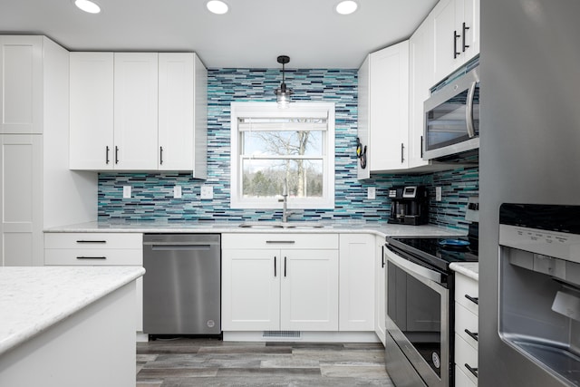 kitchen featuring recessed lighting, decorative backsplash, appliances with stainless steel finishes, white cabinets, and a sink