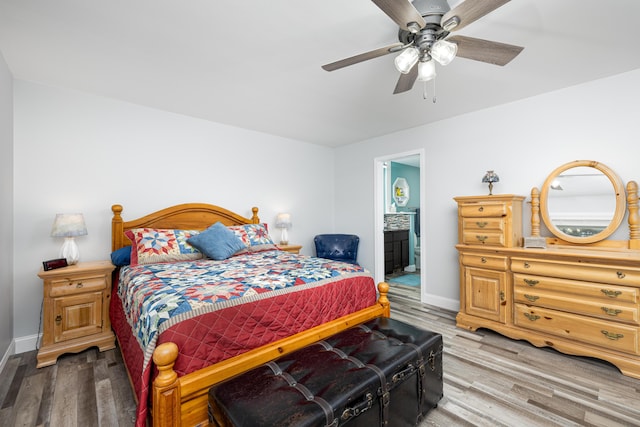 bedroom with ceiling fan, connected bathroom, baseboards, and wood finished floors