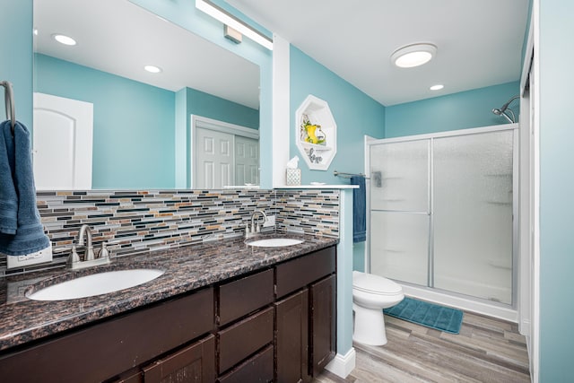 bathroom featuring wood finished floors, a stall shower, a sink, and decorative backsplash