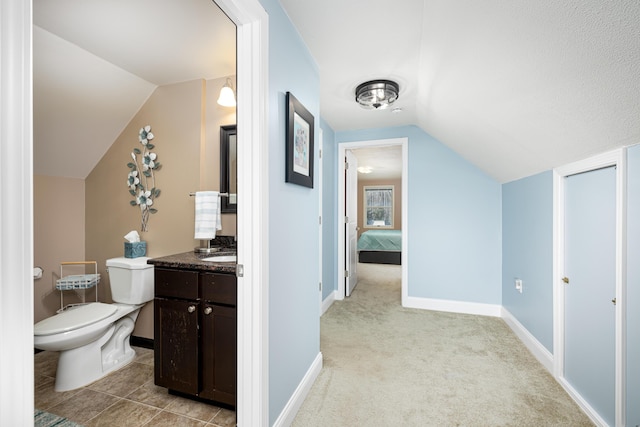 bathroom featuring toilet, vaulted ceiling, vanity, and baseboards