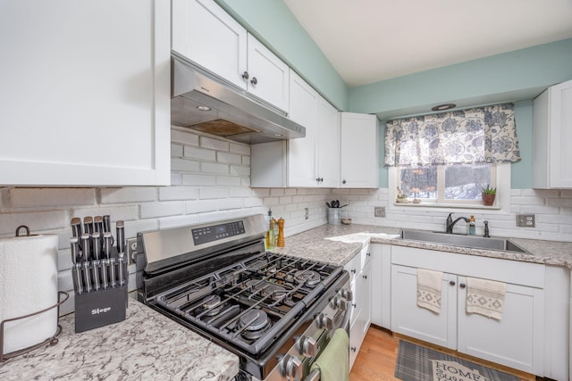 kitchen featuring stainless steel gas range oven, white cabinetry, and a sink