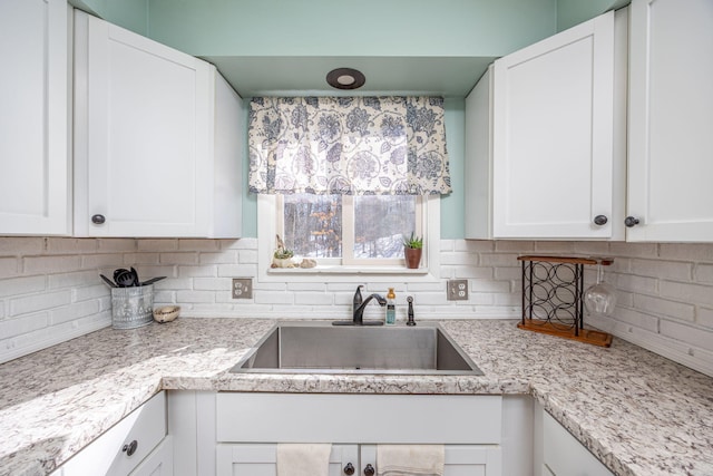 kitchen featuring tasteful backsplash, white cabinets, and a sink