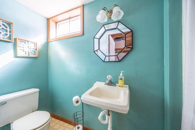 bathroom with baseboards, a sink, toilet, and tile patterned floors