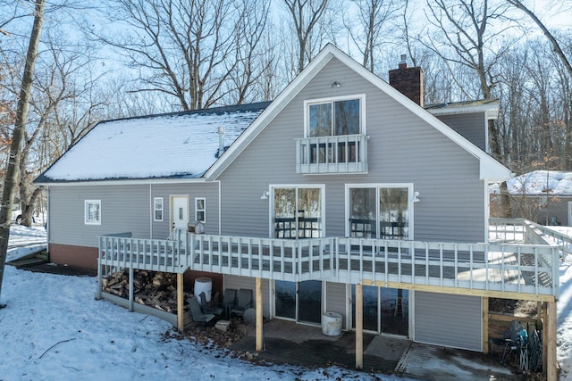 snow covered property featuring a deck and a chimney