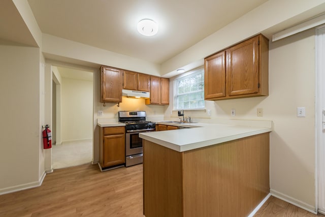 3048 Turnberry Ln, Ann Arbor, MI 48108 - kitchen with gas stove, under cabinet range hood, a peninsula, and brown cabinetry