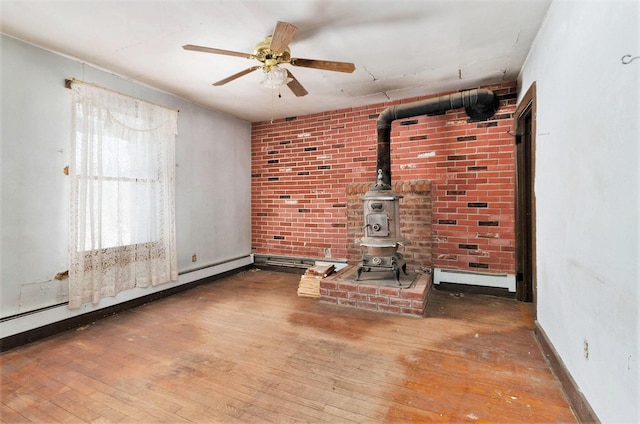 11333 Stony Creek Rd, Milan, MI 48160 - unfurnished living room featuring a wood stove, wood-type flooring, baseboard heating, and ceiling fan