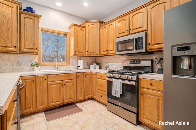 kitchen with tasteful backsplash, stainless steel appliances, a sink, and light countertops