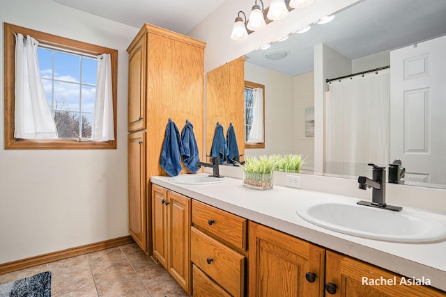 bathroom with tile patterned floors, a sink, baseboards, and double vanity