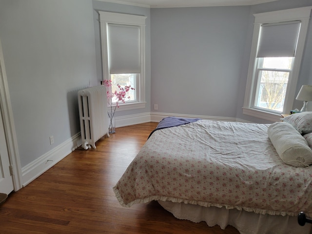 bedroom featuring radiator heating unit, baseboards, and wood finished floors