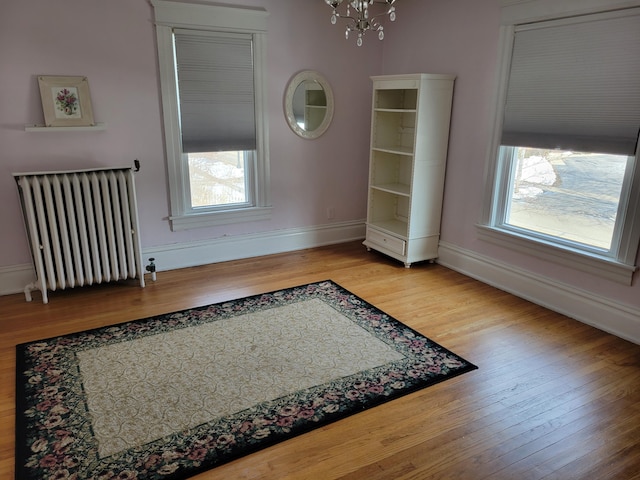 home office with a chandelier, baseboards, radiator heating unit, and wood finished floors