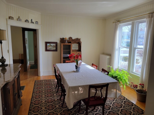 dining space featuring radiator, light wood-type flooring, visible vents, and baseboards