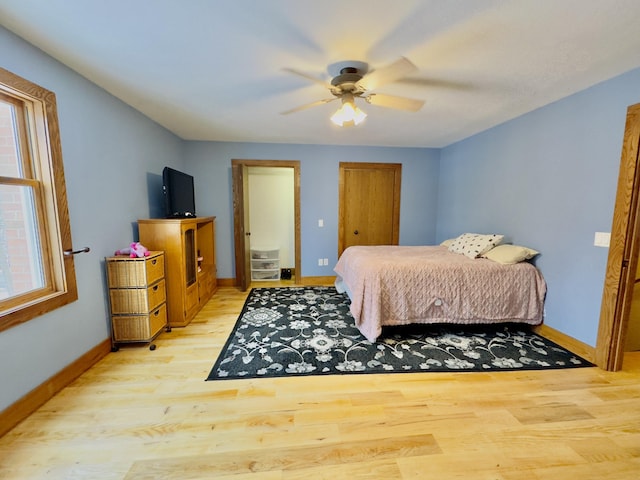 bedroom with ceiling fan, light wood-style flooring, and baseboards