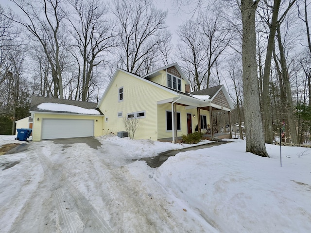 view of snowy exterior with a garage and a porch