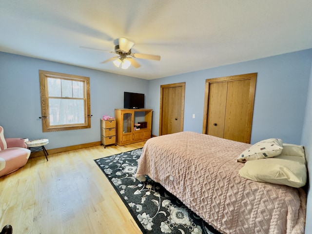 bedroom with multiple closets, ceiling fan, light wood-style flooring, and baseboards