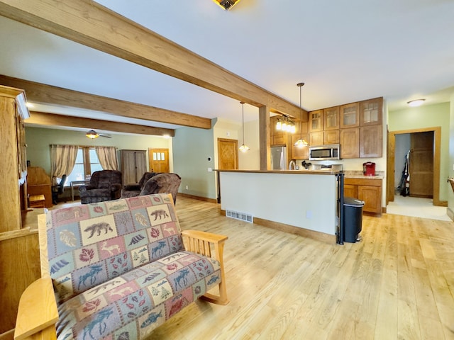 kitchen with decorative light fixtures, stainless steel appliances, brown cabinetry, glass insert cabinets, and open floor plan