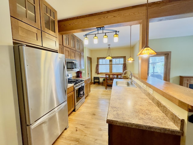 kitchen featuring decorative light fixtures, stainless steel appliances, light countertops, glass insert cabinets, and a sink