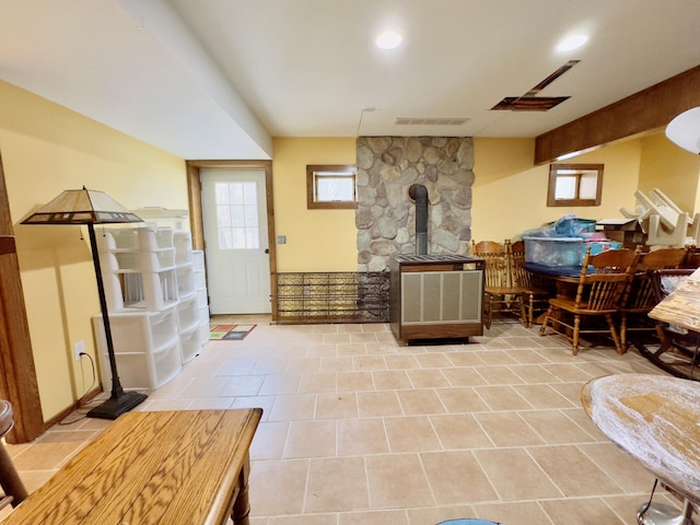 interior space featuring a wood stove, visible vents, beam ceiling, and recessed lighting